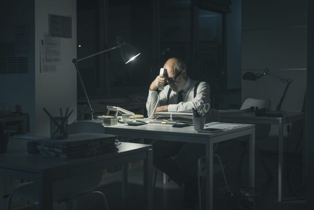 Mann sitzt nachts erschöpft am Schreibtisch im Büro